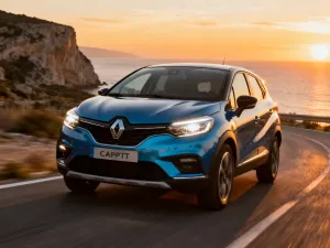 Srebrny Opel Speedster zaparkowany na krętej nadmorskiej drodze podczas zachodu słońca, podkreślający sportową sylwetkę auta.